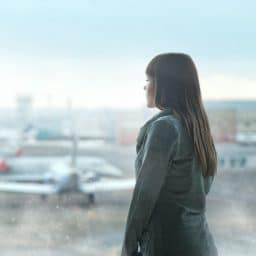 Woman looking out airport window as she waits for flight to board.